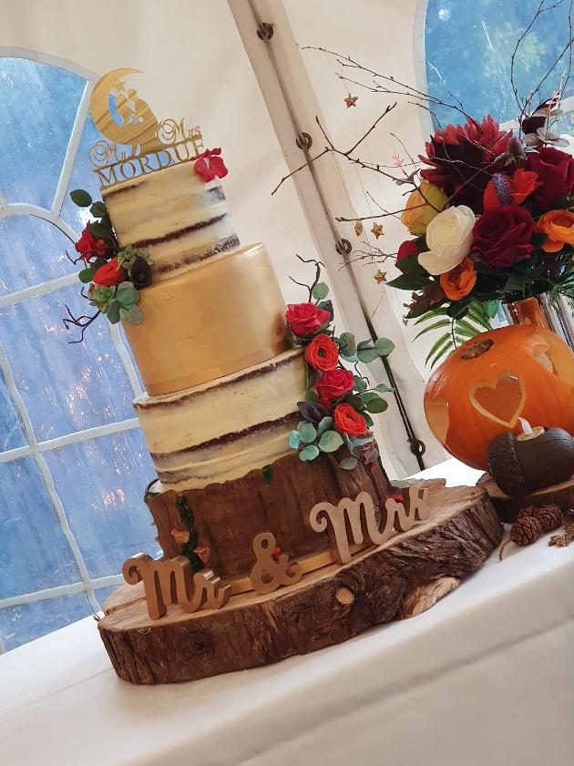 Autumn-themed wedding cake displayed on a log