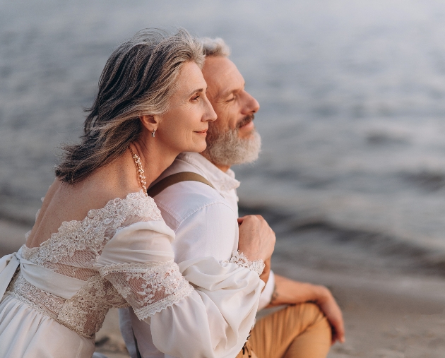 couple on beach hugging looking out to sea. 