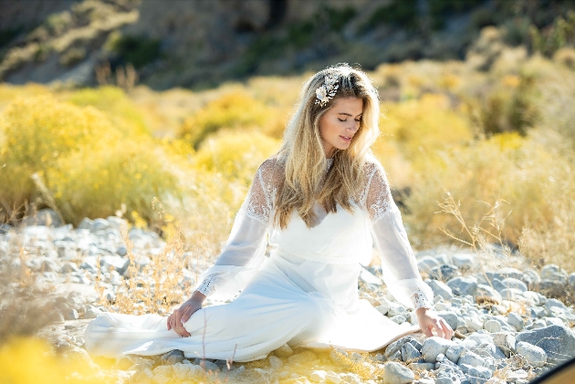 Bride sitting in a field smiling