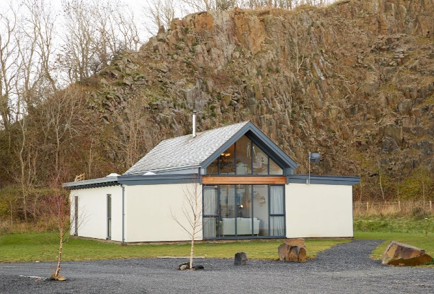 The exterior of an eco-lodge with glass doors surrounded by countryside