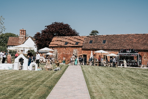 People chatting in front of a barn with tables and chairs around them