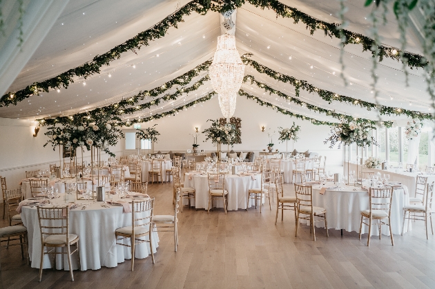 A large room with a draped ceiling decorated with flowers filled with tables and chairs