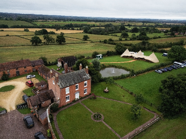 Birdseye view of a red brick building with three tipis in the grounds