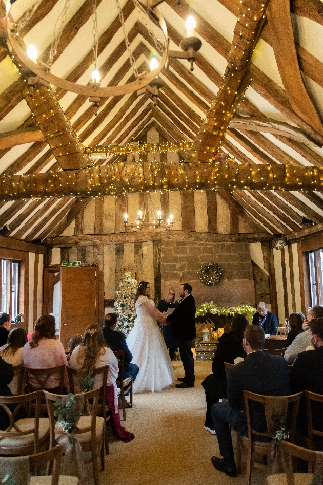 A bride adn groom getting married surrounded by friends and family in a barn