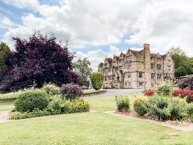 The exterior of a grand brick building surrounded by beautiful gardens