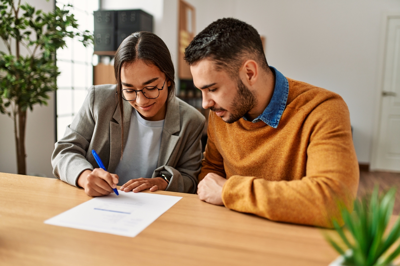 couple signing a document at a table