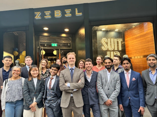 A group of people standing outside a store called Zebel