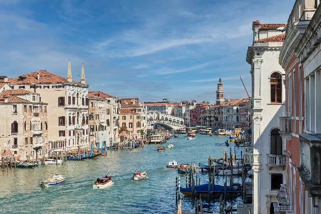 A river with boats sailing down it with large white buildings on the river