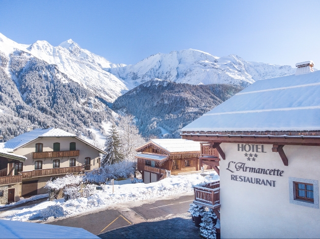 Three buildings with snow covered mountains in the background