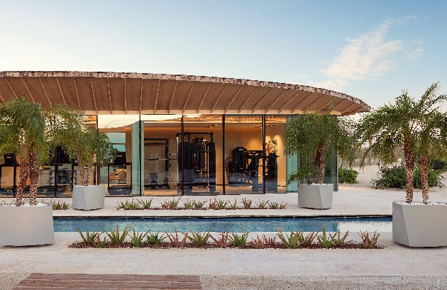 A building with a wooden roof and glass doors behind an outdoor swimming pool